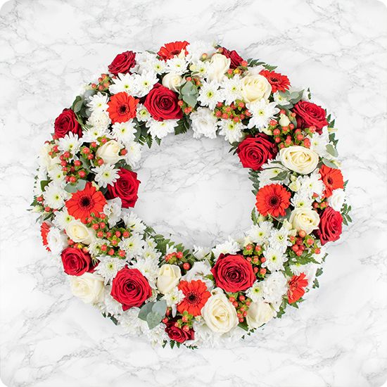 couronne de deuil composée de majestueuses roses et d'élégantes fleurs de saison dans des teintes rouges et blanches,
